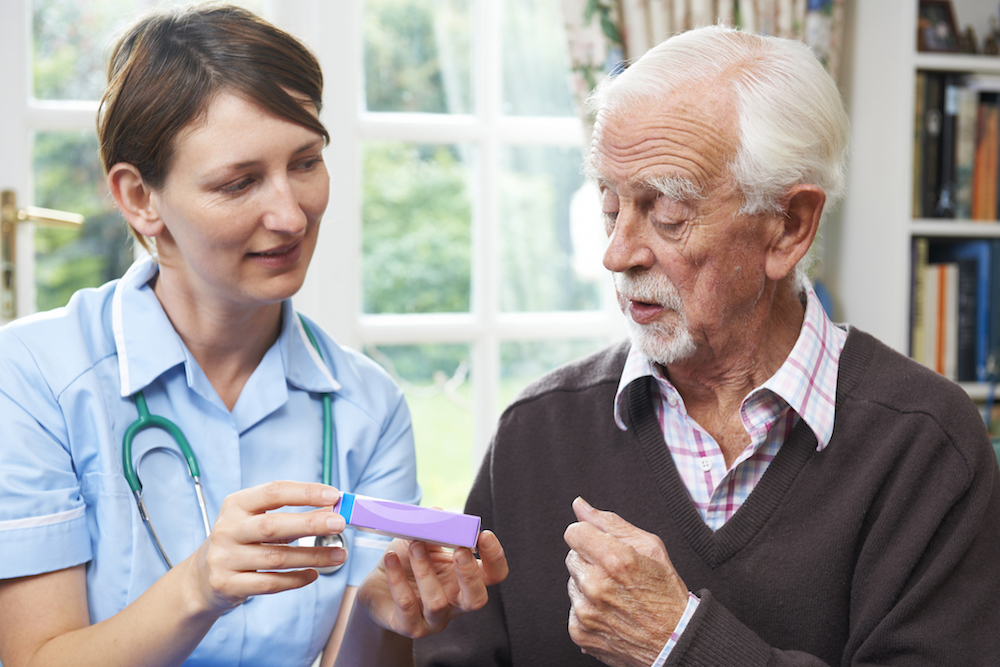medication aide providing assistance to older man